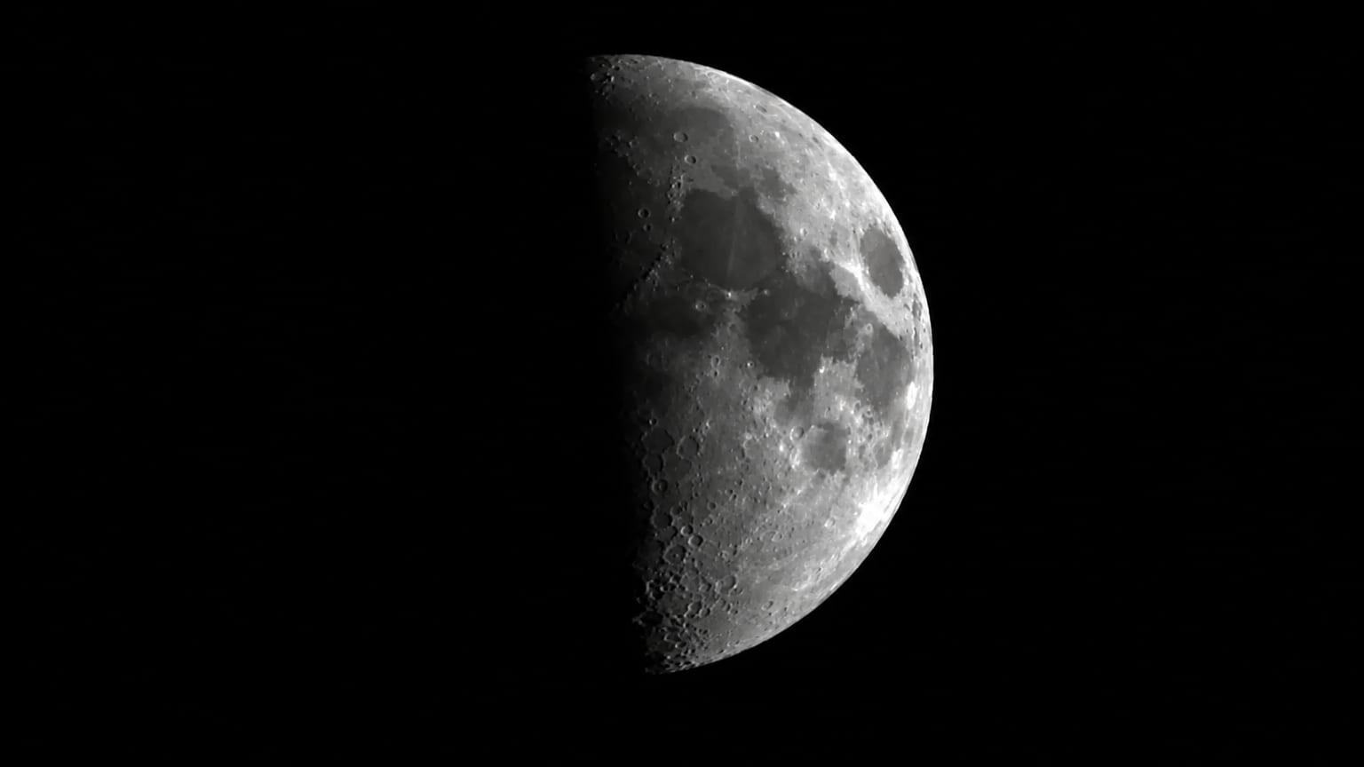 The Moon, half lit, against a black sky